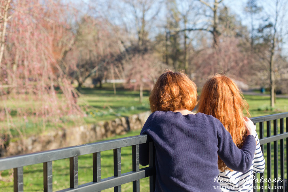 mom and daughter overlook fence in park