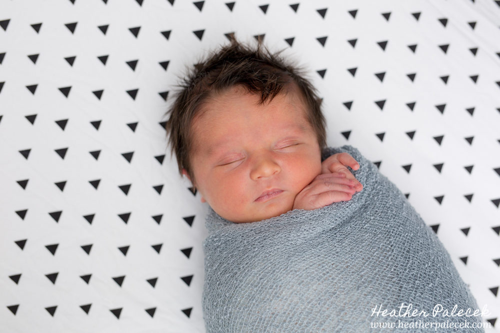 newborn laying on triangle pattern sheet