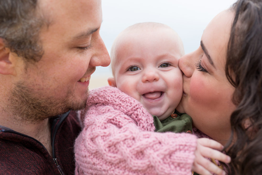 close up photo of parents kissing kids cheeks