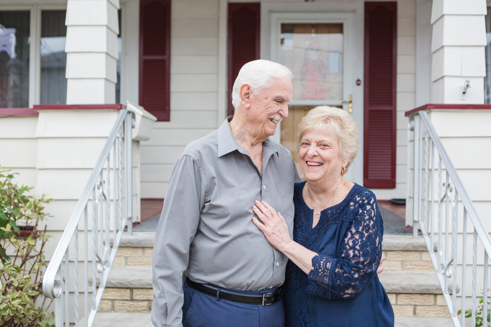 grandparents look at each other and laugh on front porch