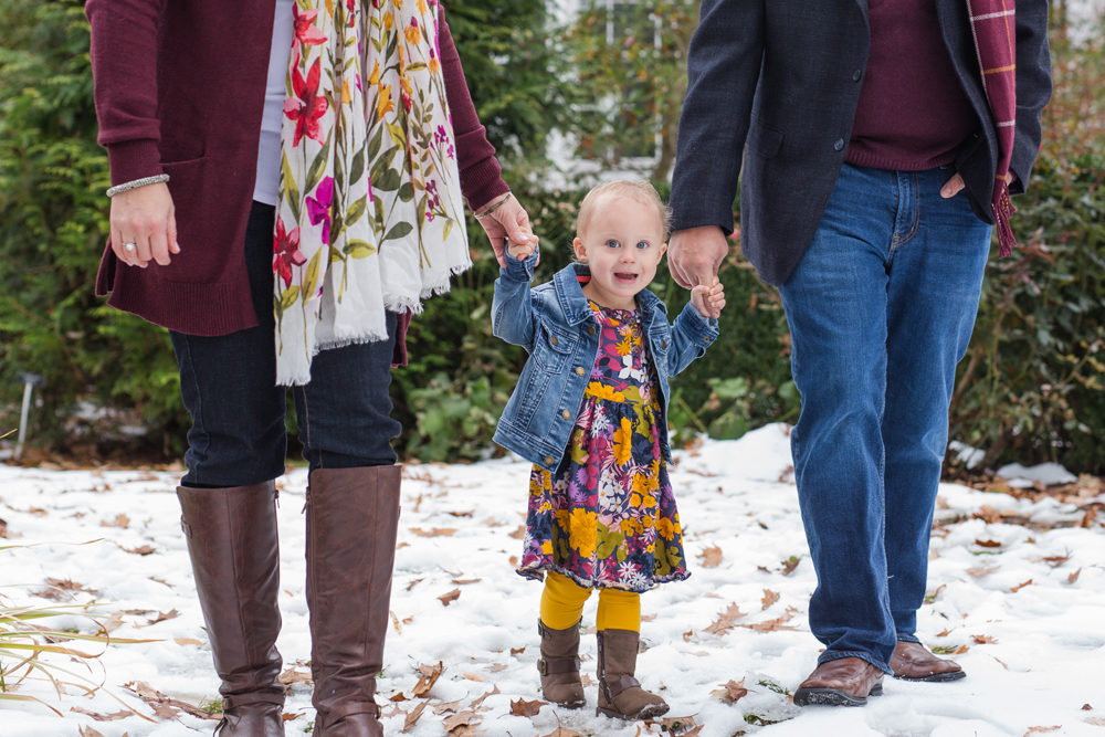 girl holding parents hands walking