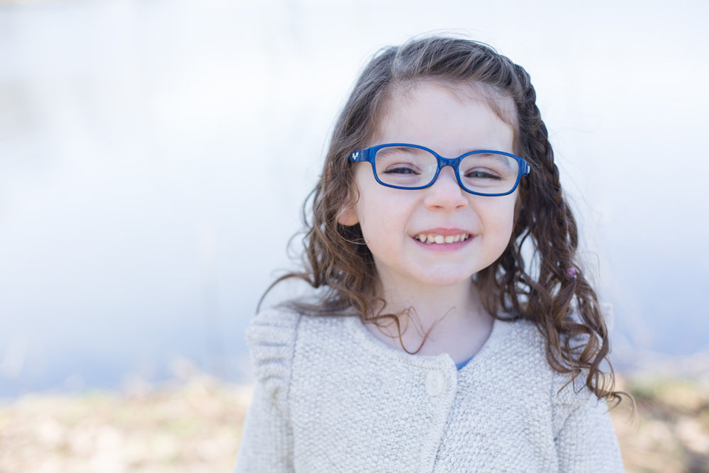 girl in blue glasses poses by lake
