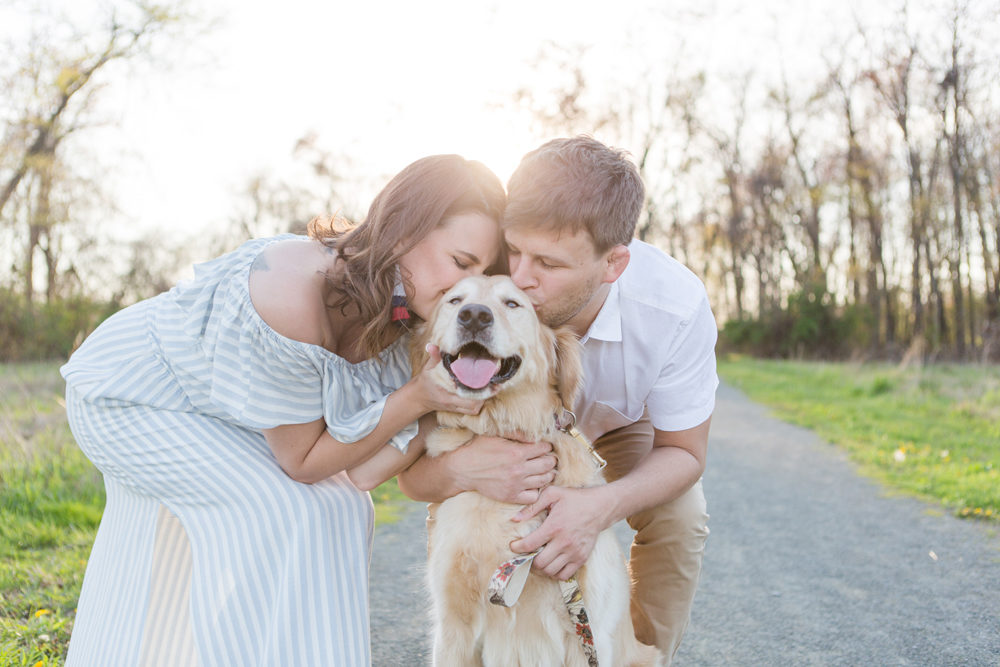 couple kissing dog on head