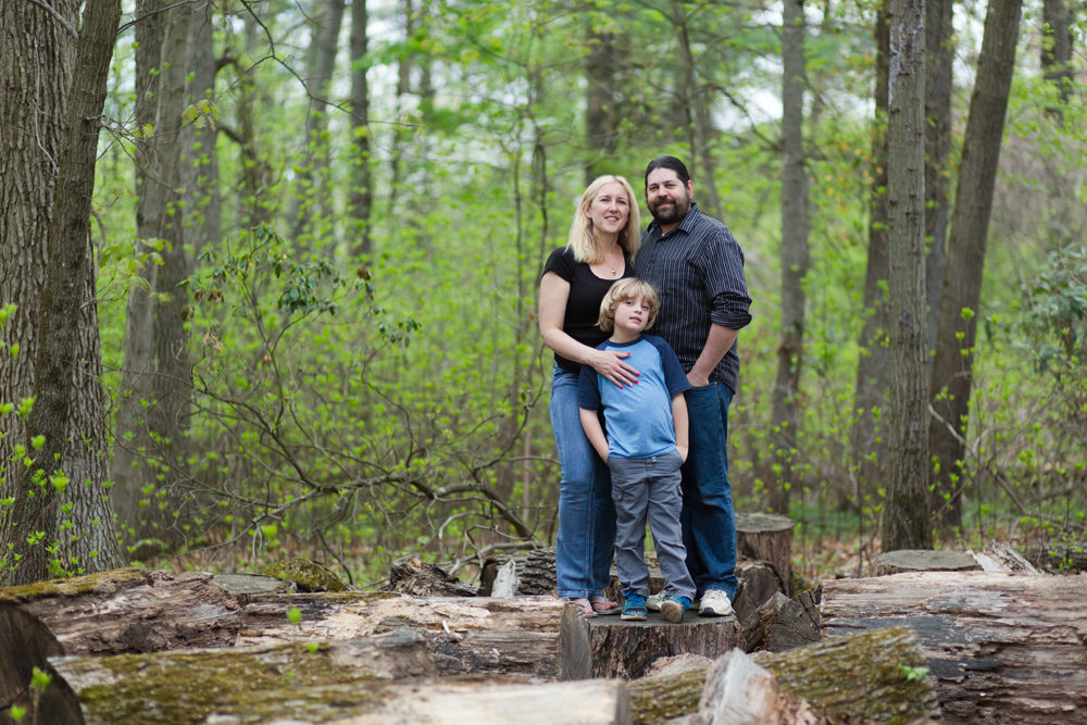 family of three posing in woods