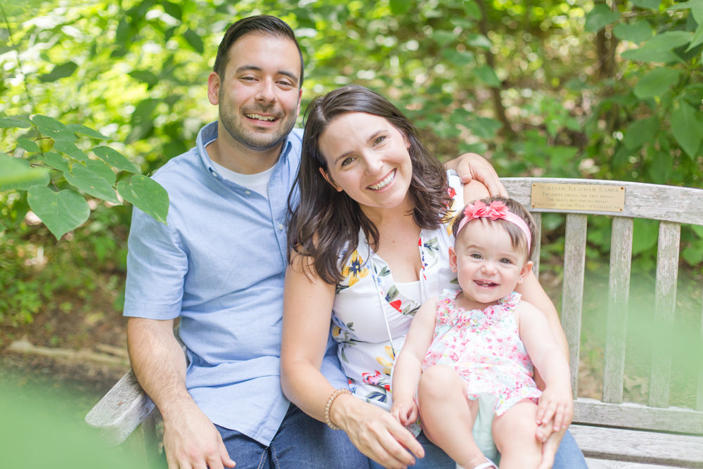 family of three pose sitting on bench