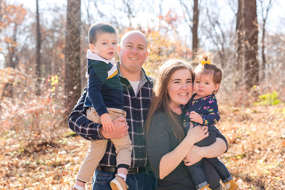 family of four posing in woods