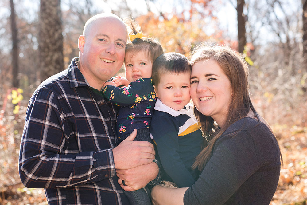 family of four posing in woods