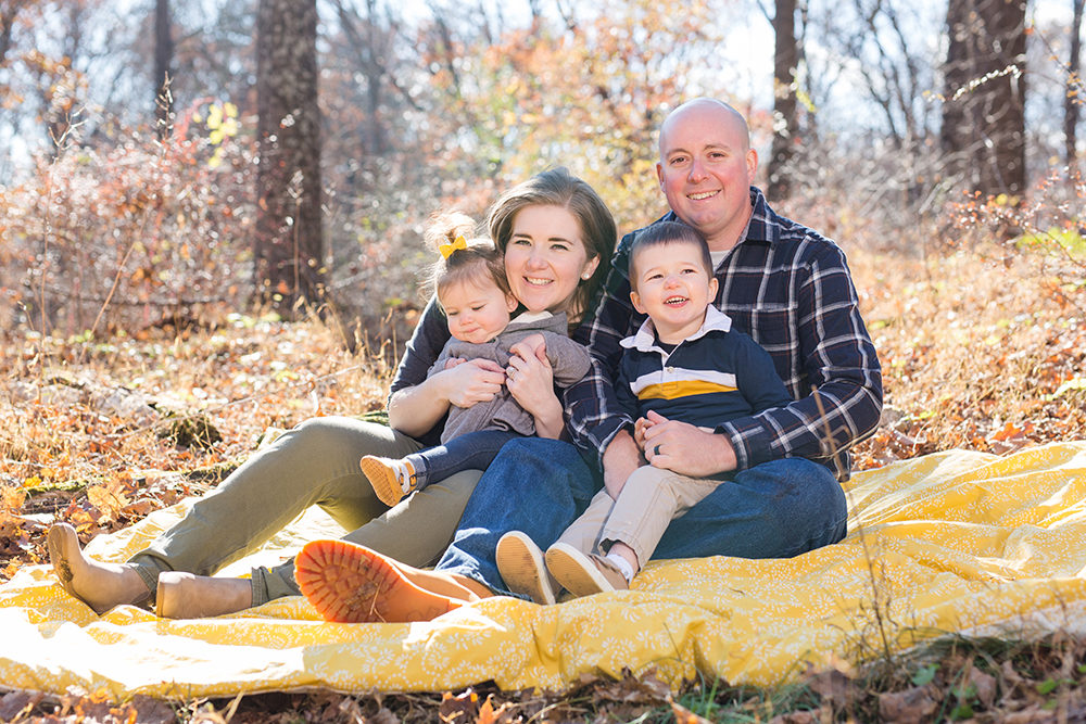 family of four posing in woods