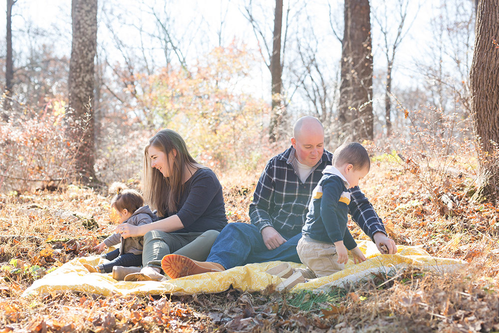 family of four plays on blanket candidly