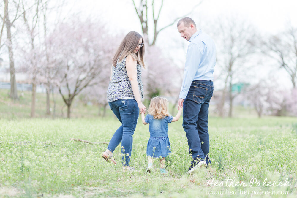 mom and dad hold hands and walk with daughter