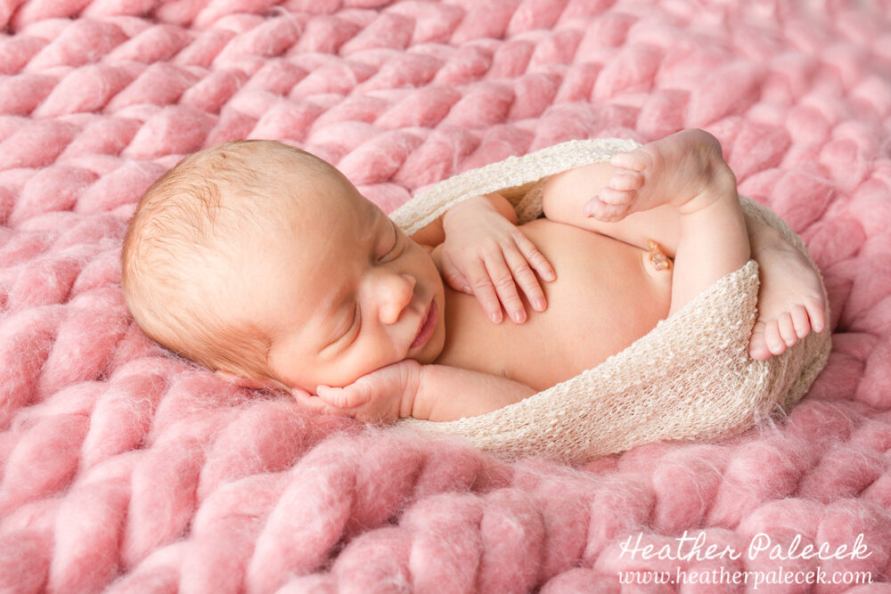 newborn girl portrait in egg pose on pink crotchetted blanket