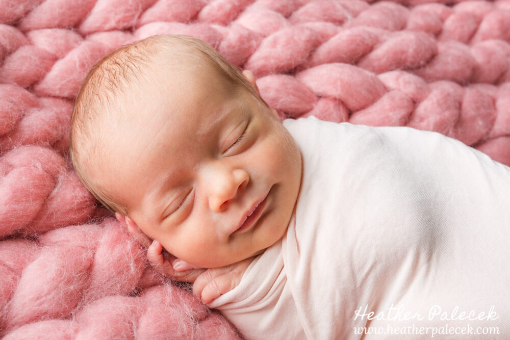 newborn girl posed on pink crotcheted blanket