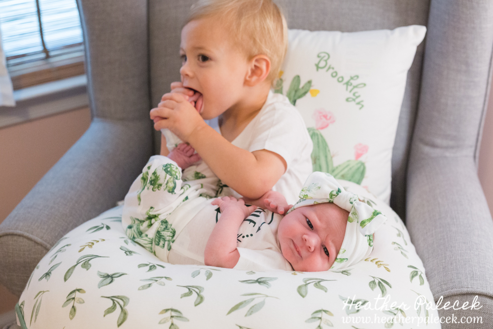 brother holds baby sister in nursery