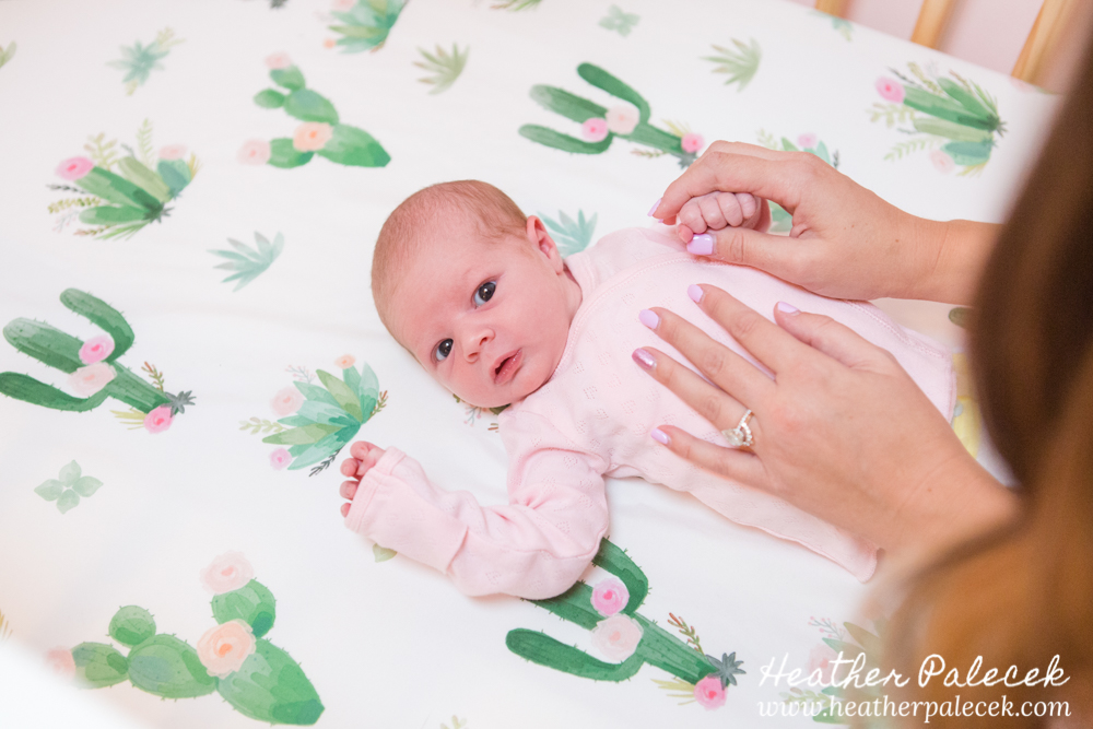 newborn girl lies in crib with cactus sheets