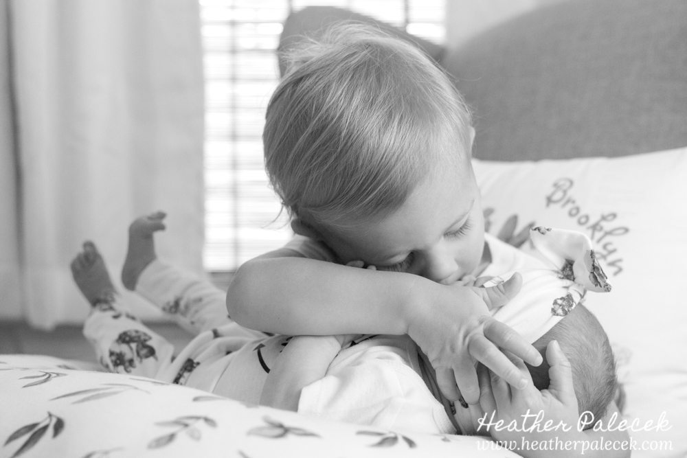 brother holds baby sister in nursery