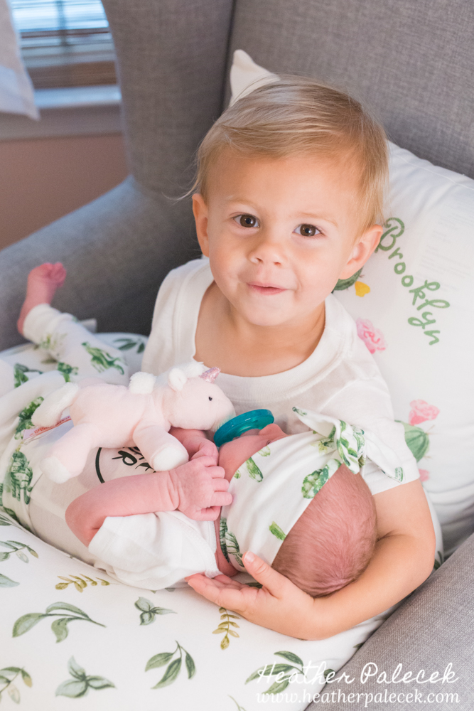 brother holds baby sister in nursery