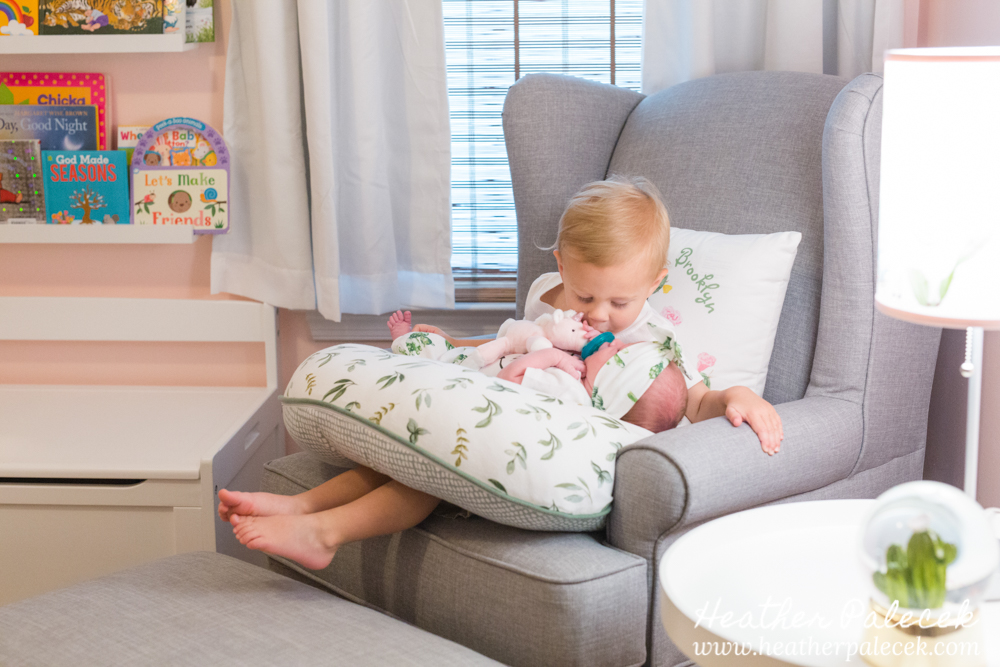 brother holds baby sister in nursery