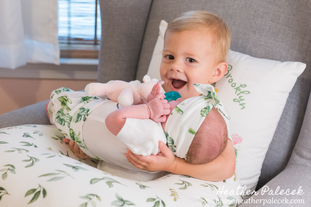 brother holds baby sister in nursery